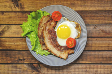The concept of the English Breakfast: fried egg with bacon, orange juice and vegetables. Free space for text, top view.