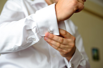 The groom fasten cufflinks on the cuffs of the shirt. The morning gatherings of the groom on the wedding day. Businessman fasten cufflinks on the cuffs of the shirt.