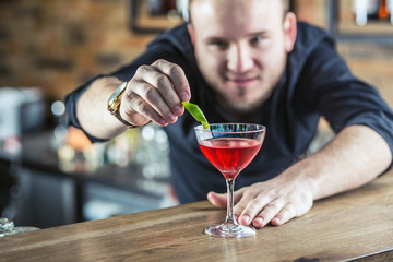 Barman in pub or restaurant  preparing a cocktail drink