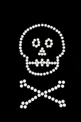 Skull and bones of white tablets on black background