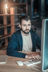 Computer programming. Pleasant charming IT guy using computer while typing and posing at table