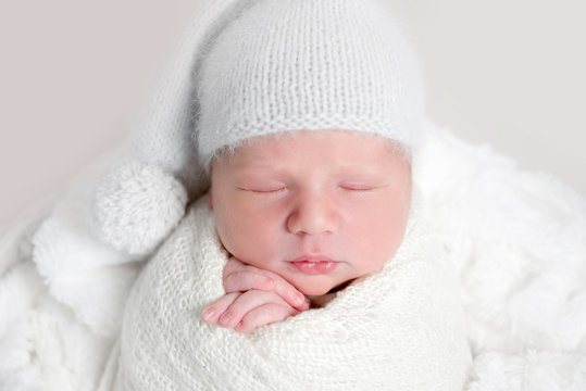 Newborn baby in white wrap laying on basket