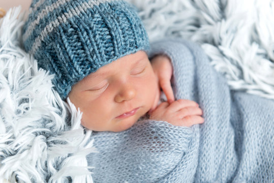 Newborn infant sleeping in box among blue blankets