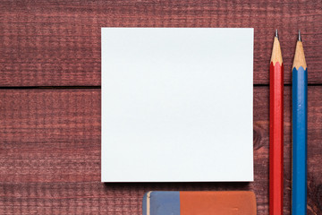 Sticky notes next to a blank sheet of paper. Supplies stationery on a wooden texture table. Trendy minimalism. Top view