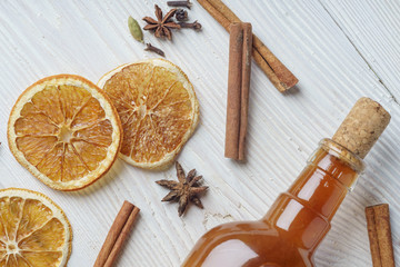 Bottle of fresh alcoholic tincture with cinnamon, pepper, orange on the bar table