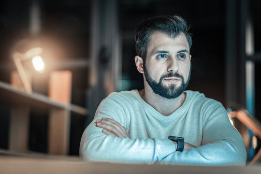 Unstoppable Progress. Musing Reflective Adorable Man Looking Aside While Crossing Arms And Posing On Blurred Background