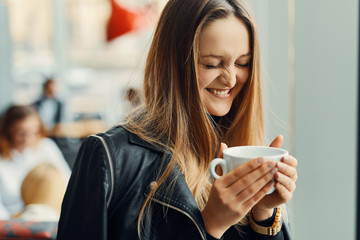 Pretty girl stand near the window with cup of coffee and smile