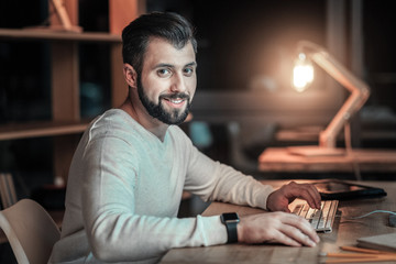 Computing machinery. Attractive vigorous IT guy posing at table while programming and looking at screen