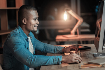 Programming basics. Positive merry IT guy sitting in profile while grinning and typing