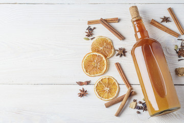 Bottle of fresh alcoholic tincture with cinnamon, pepper, orange on the bar table