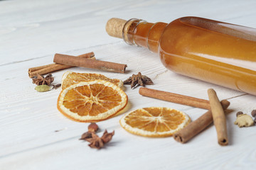 Bottle of fresh alcoholic tincture with cinnamon, pepper, orange on the bar table