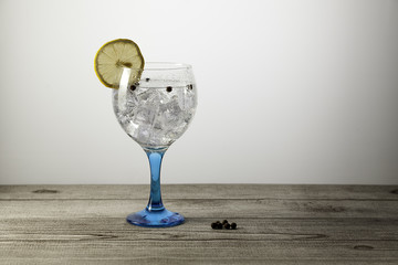 gin tonic on blue glass and peppercorns
