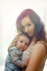Fototapeta na wymiar Pretty woman holding a newborn baby in her arms, sunlight, sunset