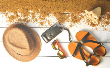 Beach accessories are laid out on a white wooden surface. Hat, camera, sandals, sunglasses. The concept of relaxing at sea. Summer beach season is open! Top view.Flat lay.