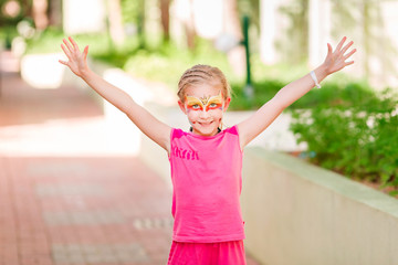 Happy little girl with face art paint in the park.