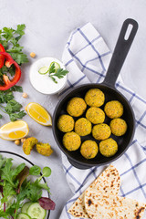 Traditional middle eastern homemade dishes falafel, pita, served with vegetables and spices on concrete background table. Top view