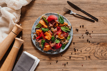 top view of delicious salad with mussels, vegetables and jamon on wooden table