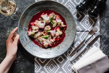 cropped shot of human hand and delicious snack with dorado on marble table top