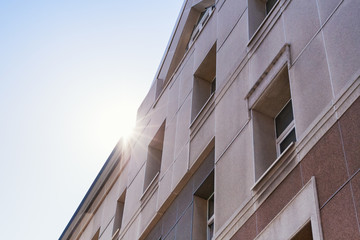 The sun's rays shining  facade of a modern beige building. 