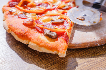 Cutting pepperoni pizza on slices with knife.