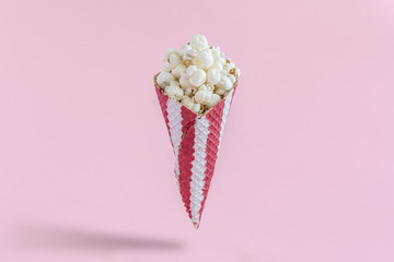 Popcorn in cone on rose background minimalistic concept.