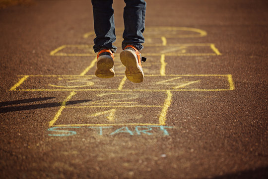 Kids playing hopscotch on playground outdoors. Hopscotch popular street game.