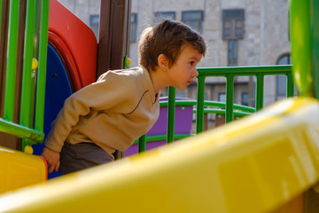 Fototapeta na wymiar Cute caucasian child boy having fun to play slider in the playground