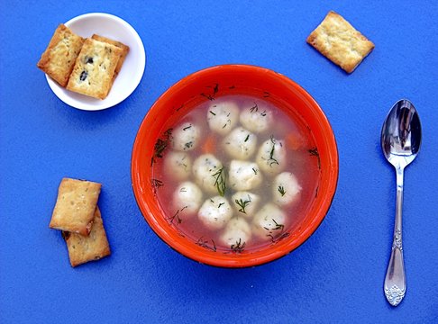 Light vegetable soup with semolina dumplings on a blue background