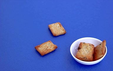 Crispy salted wheat crackers in a white plate on a blue background