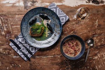 top view of delicious cream soup with jamon and fried zander on wooden table