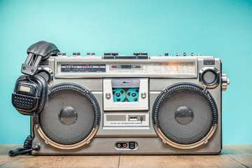 Retro outdated portable stereo boombox radio cassette recorder from circa late 70s with aged headphones front aquamarine wall background. Listening music concept. Vintage old style filtered photo - obrazy, fototapety, plakaty