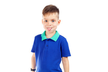 A preschool boy in a blue T-shirt is showing his tongue