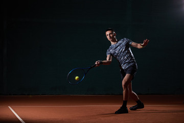 Fototapeta na wymiar young professional tennis player with a blue racket hitting a forehand, black background