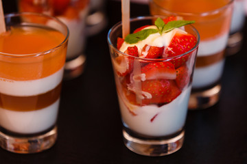layered dessert with strawberries, biscuit cake and cream cheese on a dark wood background. tinting. selective focus