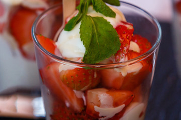 layered dessert with strawberries, biscuit cake and cream cheese on a dark wood background. tinting. selective focus