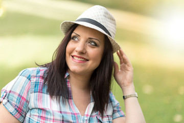 Portrait of beautiful young woman with hat in park, light effect