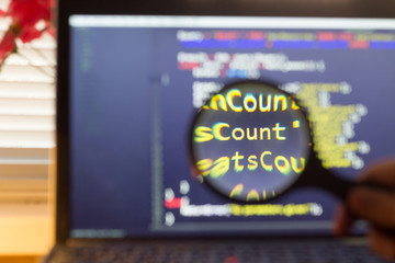 PHP back-end code zoomed through a magnifier. Computer programming source code lookup. Abstract screen of web developer. Code is created by myself.