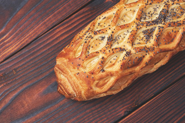 Baked bun with puff pastry, sprinkled with poppy seeds on a dark wooden background. Close-up. Food background.