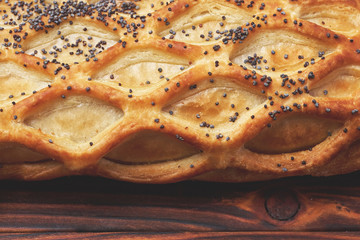 Baked bun with puff pastry, sprinkled with poppy seeds on a dark wooden background. Close-up. Food background.