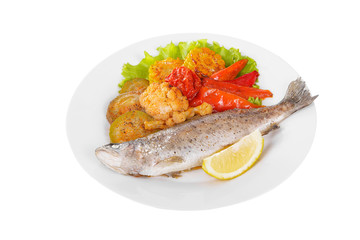 Fish trout whole with a head baked fried over an open fire with side dish vegetables a slice of...