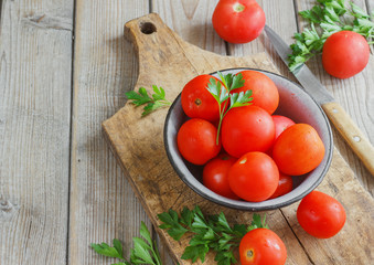 red tomatoes on a wooden board with parsley. country style