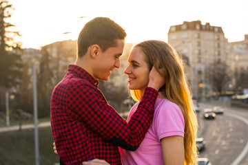 Fototapeta premium The man is going to kiss the young woman and touches her hair on sunset