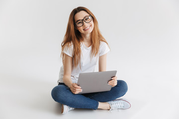 Naklejka premium Smiling woman in t-shirt and eyeglasses sitting on the floor