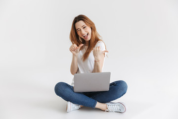 Happy woman in t-shirt sitting on floor with laptop computer
