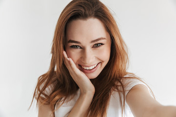 Fototapeta premium Pleased woman in casual clothes making selfie while holding cheek