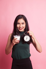 Fototapeta premium Healthy Asian woman drinking glass of milk hold clock.