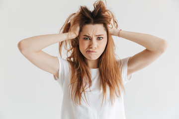 Confused woman in t-shirt holding hair and looking at camera