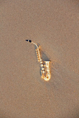 The golden alto saxophone lies on the sand or on the beach. Musical cover and creative. Design with...