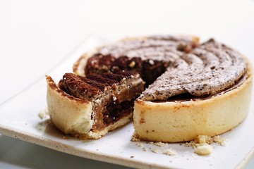 A tart was cut to a small piece and placed together, Delicious dessert, Italian dessert, rounded tiramisu tart placed on white plate and placed on white table. Tiramisu cake with Cinnamon and Coffee