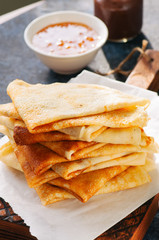 Close up of delicious crepes (blinis)  on a wooden board on a blue stone background.